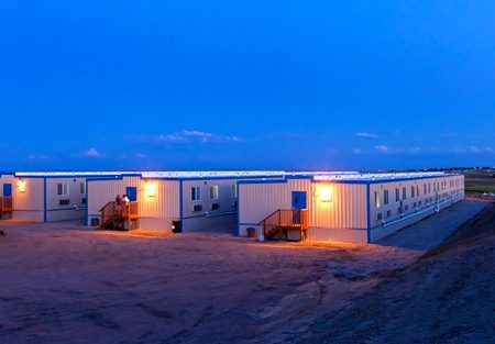 Erected camp exterior at dusk, lights on